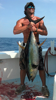 muscular man holding fish he caught on finest kind fishing charter