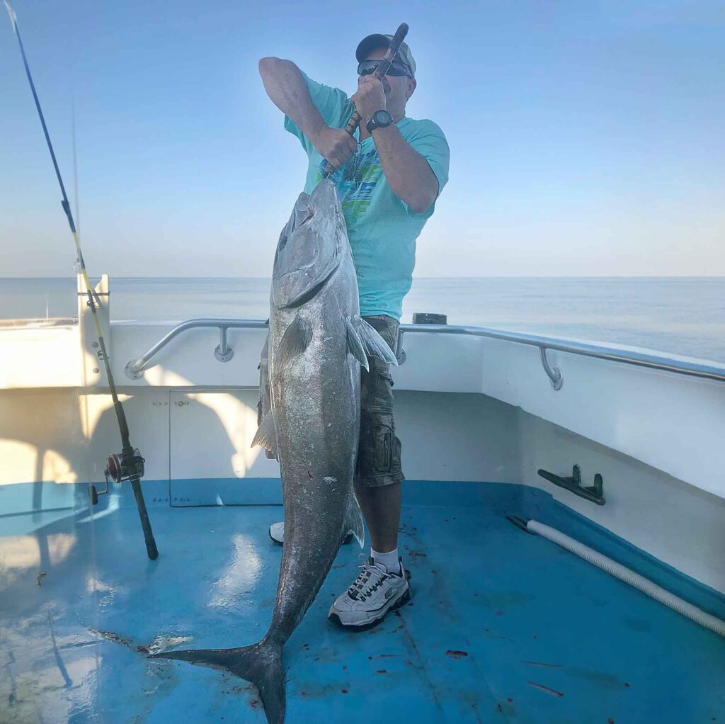 A man holding his 90 pound amberjack caught off the Finest Kind Charter Boat.